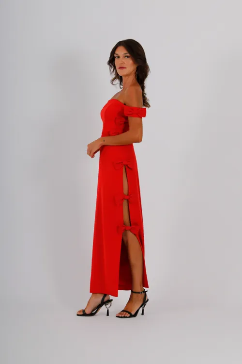 Vestido midi de crepe con una delicada abertura lateral, combinado con lazos de tafeta que añaden sofisticación. El escote bardot, está adornado con lazos en el hombro los cuales realzan la elegancia y feminidad del diseño.