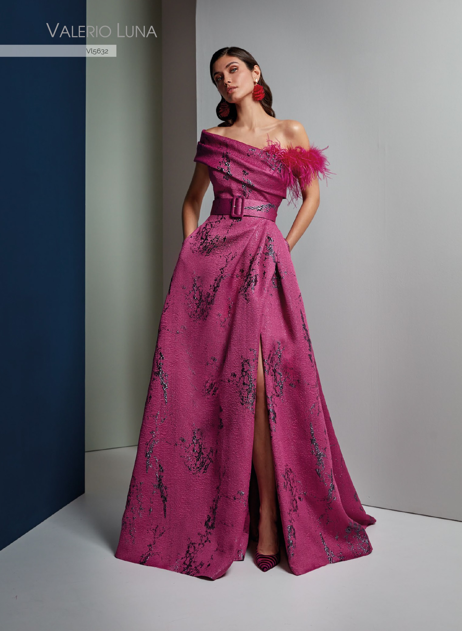 Vestido de fiesta de costura confeccionado en jacquard. El cuerpo drapeado presenta cuello vuelto en un lado y en el otro lado un tirante caido con plumas.