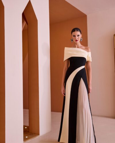 Sensacional vestido de madrina largo de fiesta bicolor confeccionado en crepé. Lleva un bonito cuello de barco, tipo bardot asimétrico y su falda tiene una abertura lateral abierta con plisado soleil. Un modelo lleno de encanto y elegancia para destacar en cualquier fiesta. De la firma Española CARLA RUIZ.