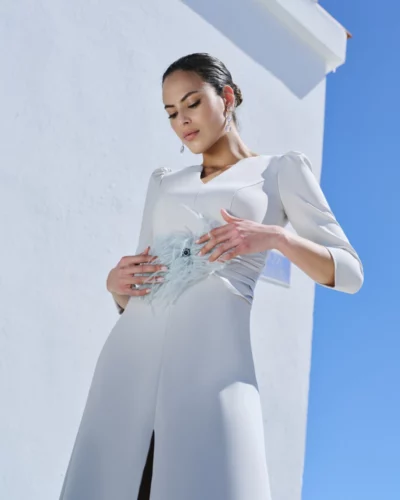 El vestido Naiara destaca por su equilibrio entre elegancia clásica y tendencia. Confeccionado en crepe estructurado, este diseño largo realza la figura gracias a su corte limpio y al fajín de satén que marca la cintura con sutileza. El adorno de plumas añade un toque de distinción y movimiento, aportando un aire sofisticado y contemporáneo. Este modelo está pensado para mujeres que buscan un vestido de fiesta elegante con personalidad propia. Una pieza versátil que combina sobriedad, textura y lujo en cada detalle.